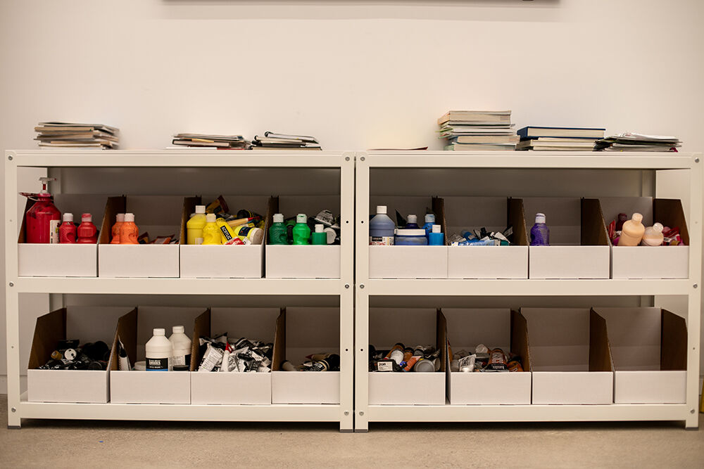 Paints sorted by colour on the studio shelves, by David Zak